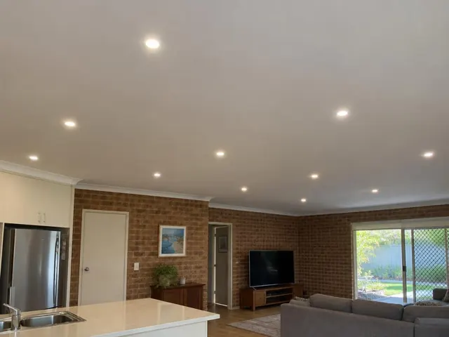 Ceiling with recessed LED downlights in a brick-walled open-plan living room in Coombabah